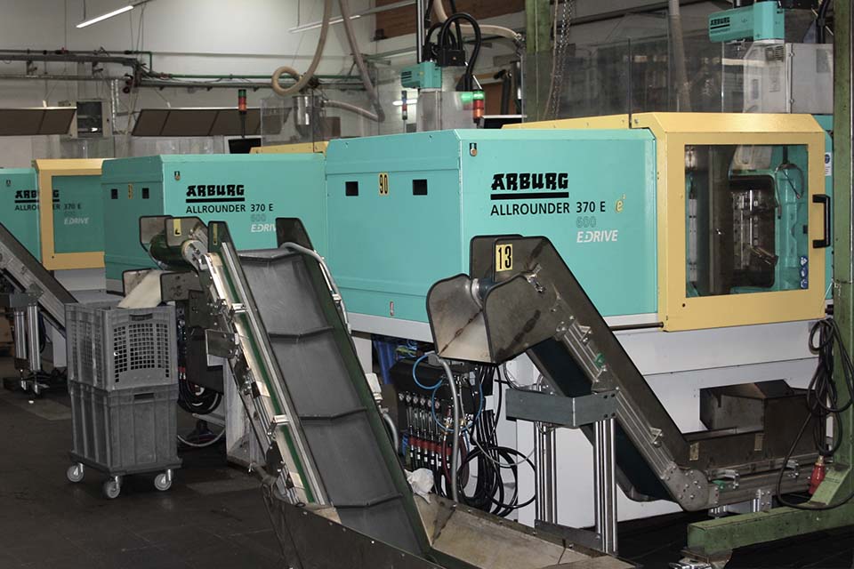 Section of the production hall with several Arburg injection molding machines lined up in a row