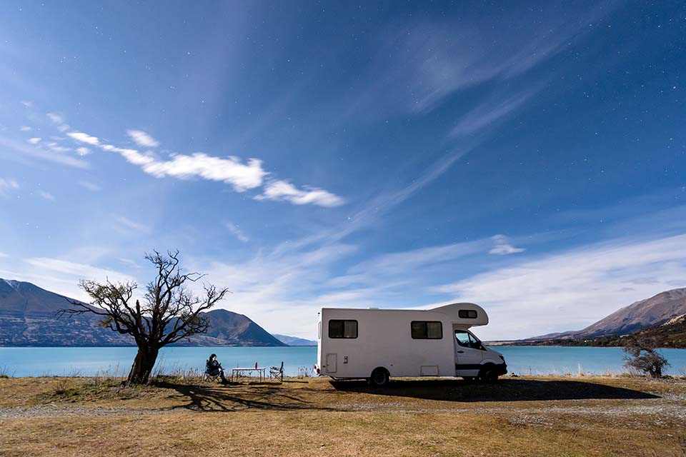 A parked motorhome in a unique lake landscape with clear blue sky