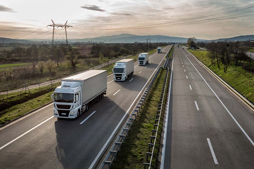 Four trucks on a motorway at dawn