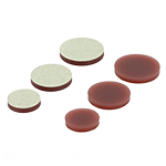 Das Bild zeigt zwei Reihen von je 3 runden Klebeplättchen aus rotbraunem Polyurethan. Die Rückseite hat eine selbstklebende mit gelblichen Papier abgedeckte Klebefläche.