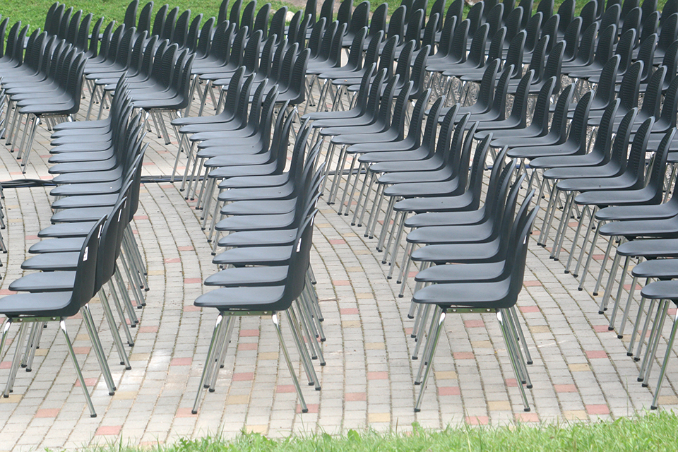Stuhlreihen im Freien auf grauen Verbundsteinen aus Beton