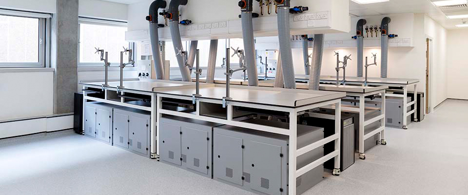 A well-lit room with workbenches fitted with extraction systems and telescopic frames