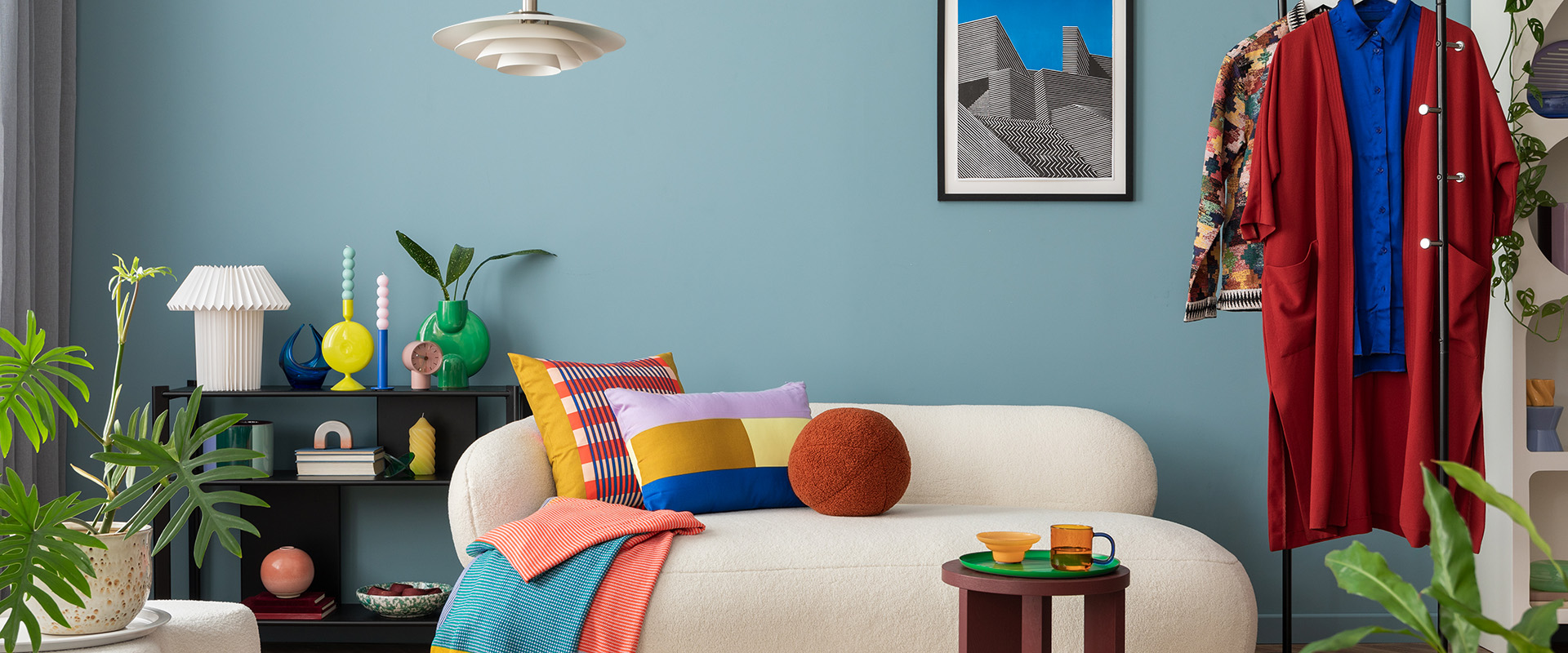 Modernes und farbenfrohes Wohnzimmer mit einem Design-Bouclé-Sofa, einem Mock-up-Poster, einem Regal, Pflanzen, Dekoartikeln und persönlichen Gegenständen