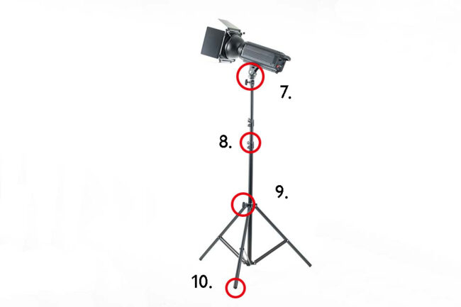 Black spotlight positioned sideways on a tripod, isolated against a white background