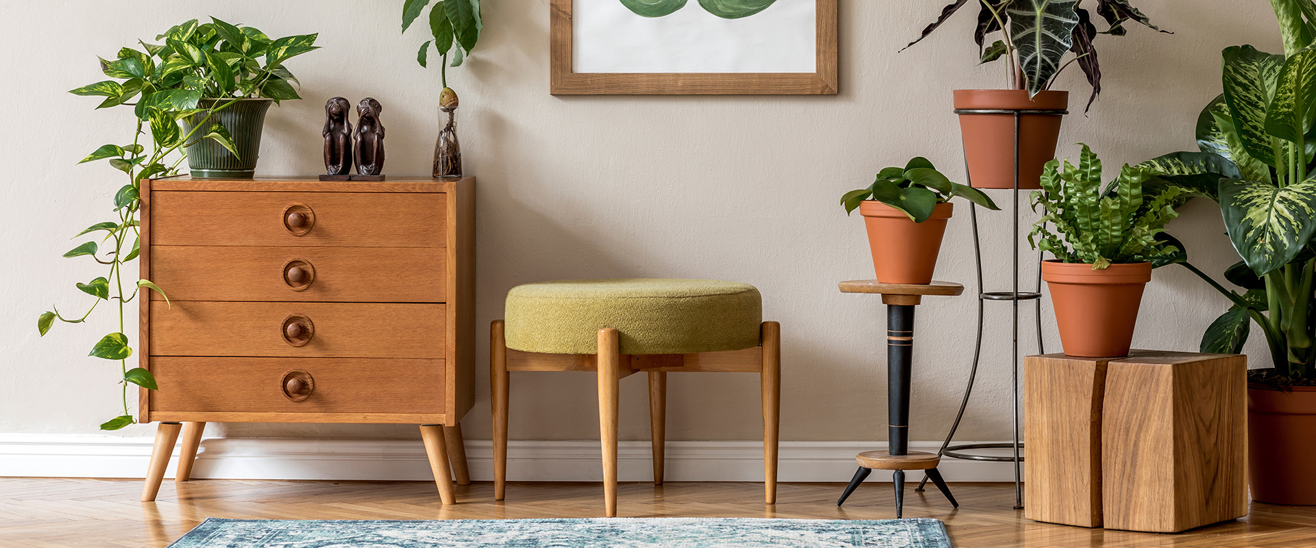 Vintage Innenarchitektur des Wohnzimmers mit stilvollen Retro-Möbel, viele Pflanzen, Kommodeund Hocker